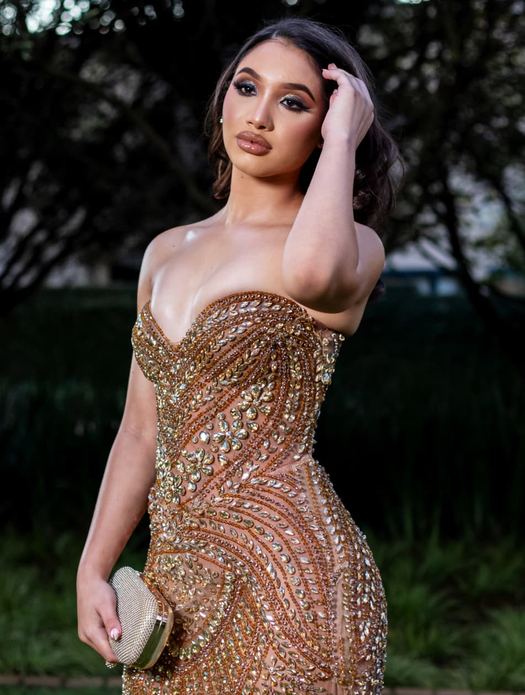 26 Karat — Rose-gold sequin over a sweetheart corset, beading tapering to a fishtail hem. Shot in the garden at dusk.