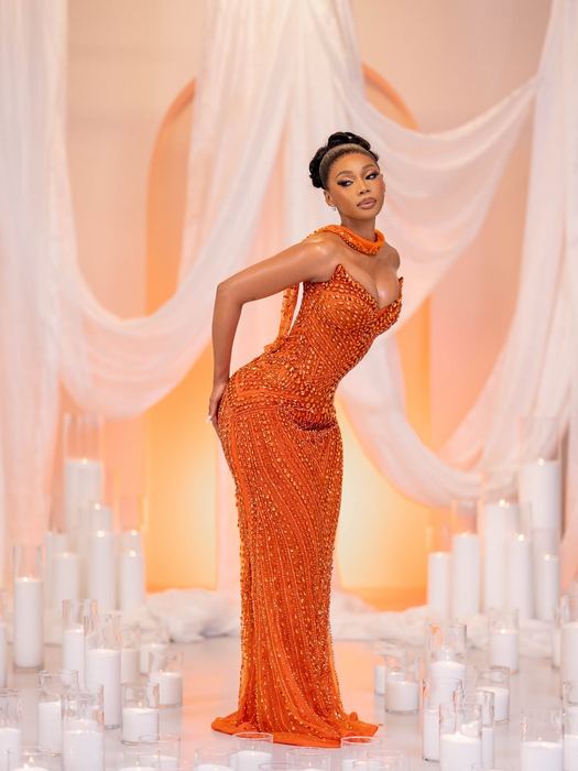 The Neil — Burnt orange crystal with a high beaded collar, standing in a field of candles.
